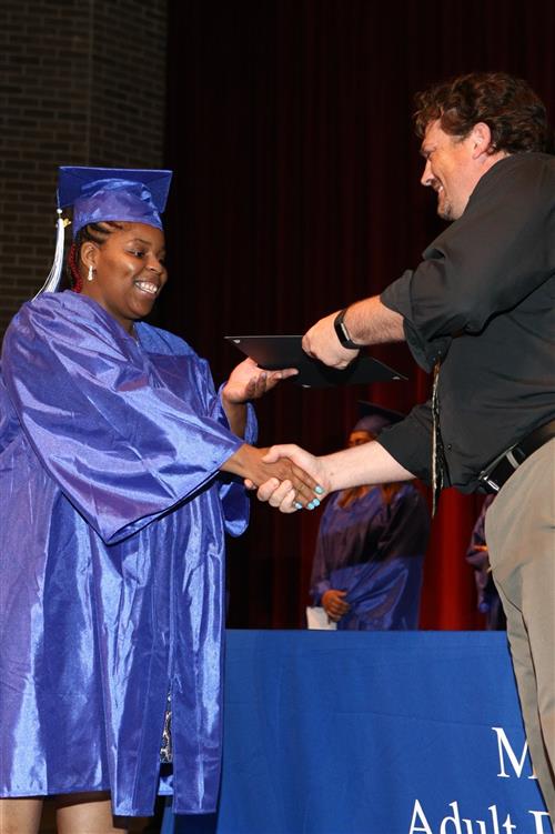 Student receiving her diploma and shaking hands with school administrator. Student receiving her diploma and shaking hands with school administrator.
